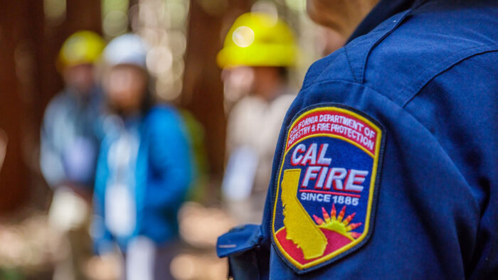 Close-up of a shoulder badge that reads "California Department of Forestry & Fire Protection: CALFIRE since 1988" in an emblem that includes the outline of the state of California and a sun on the horizon.