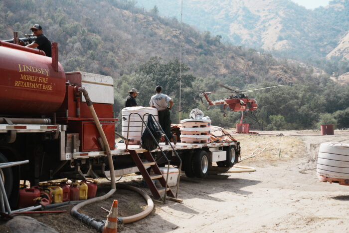 A firefighting helicopter lifts off from a mountain base.